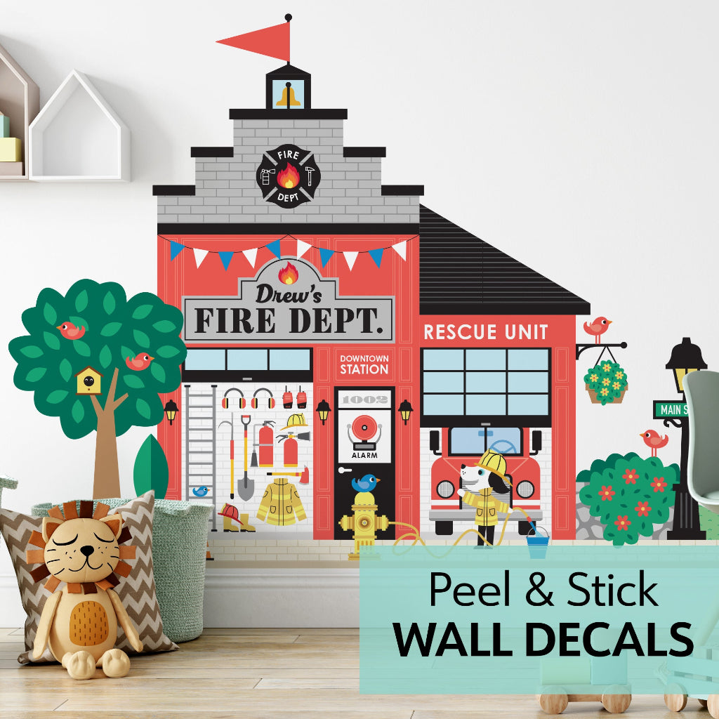 Personalised Fire Station wall decal – red ‘Drew’s Fire Dept’ building with rescue pup, tree & pillows in kids’ room, Happy Town pretend-play scene.